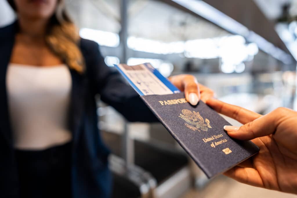 A close-up of a person holding a United States passport with a boarding pass tucked in.
